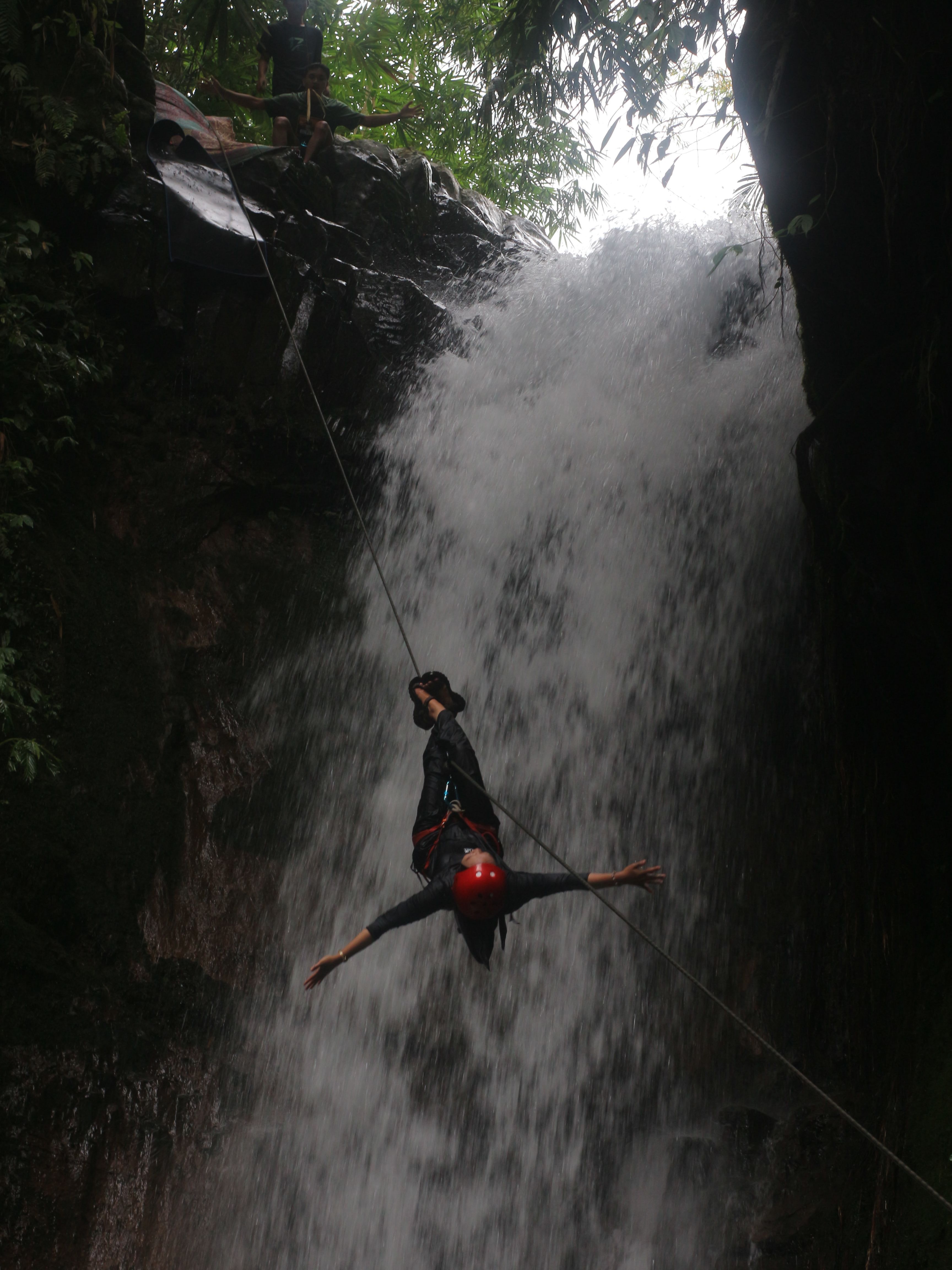 NIKMATI: Salah seorang pengunjung saat menikmati  olahraga rappelling di air terjun Tibu Bunter, Desa Jeruk  Manis, dengan bergelantungan di ketinggian 20 meter, Minggu (6/7).