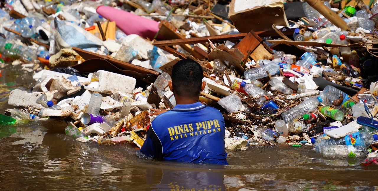 Seorang petugas PUPR Kota Mataram membersihkan sampah di bawah jembatan Unram, Minggu lalu (6/7)