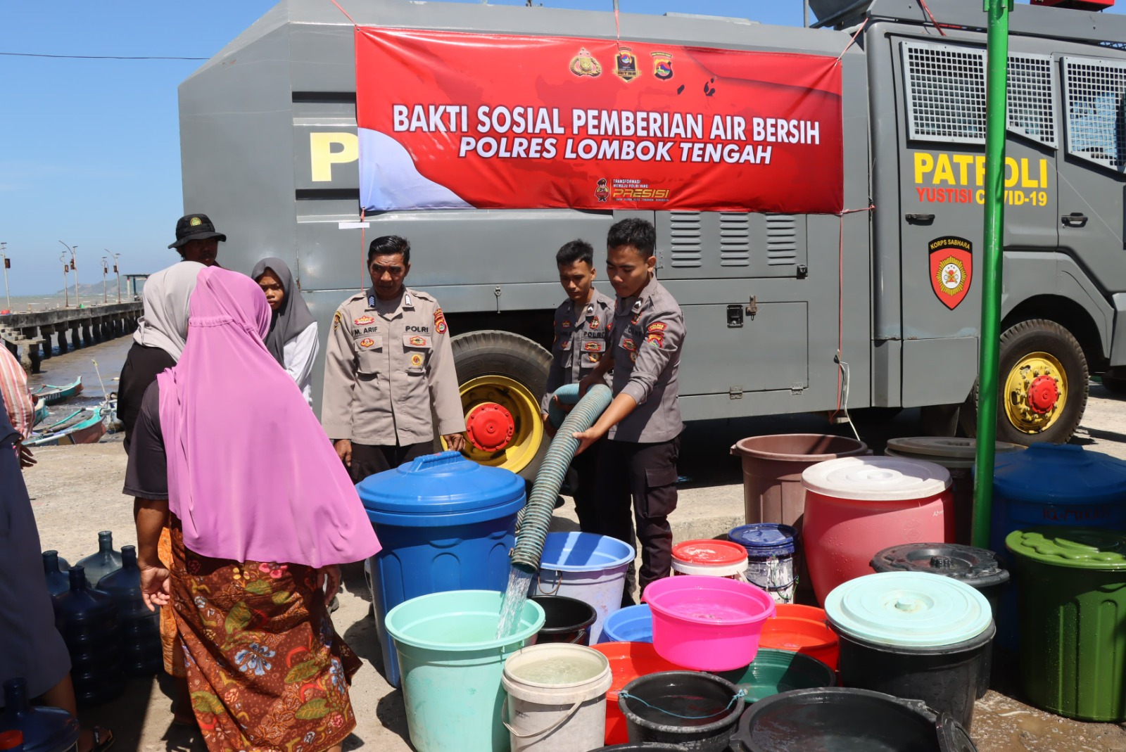 MULAI TERDAMPAK: Anggota Polres Lombok Tengah mengisi ember-ember kosong milik warga dengan air bersih di Kecamatan Praya Timur, Lombok Tengah, Selasa (9/7).