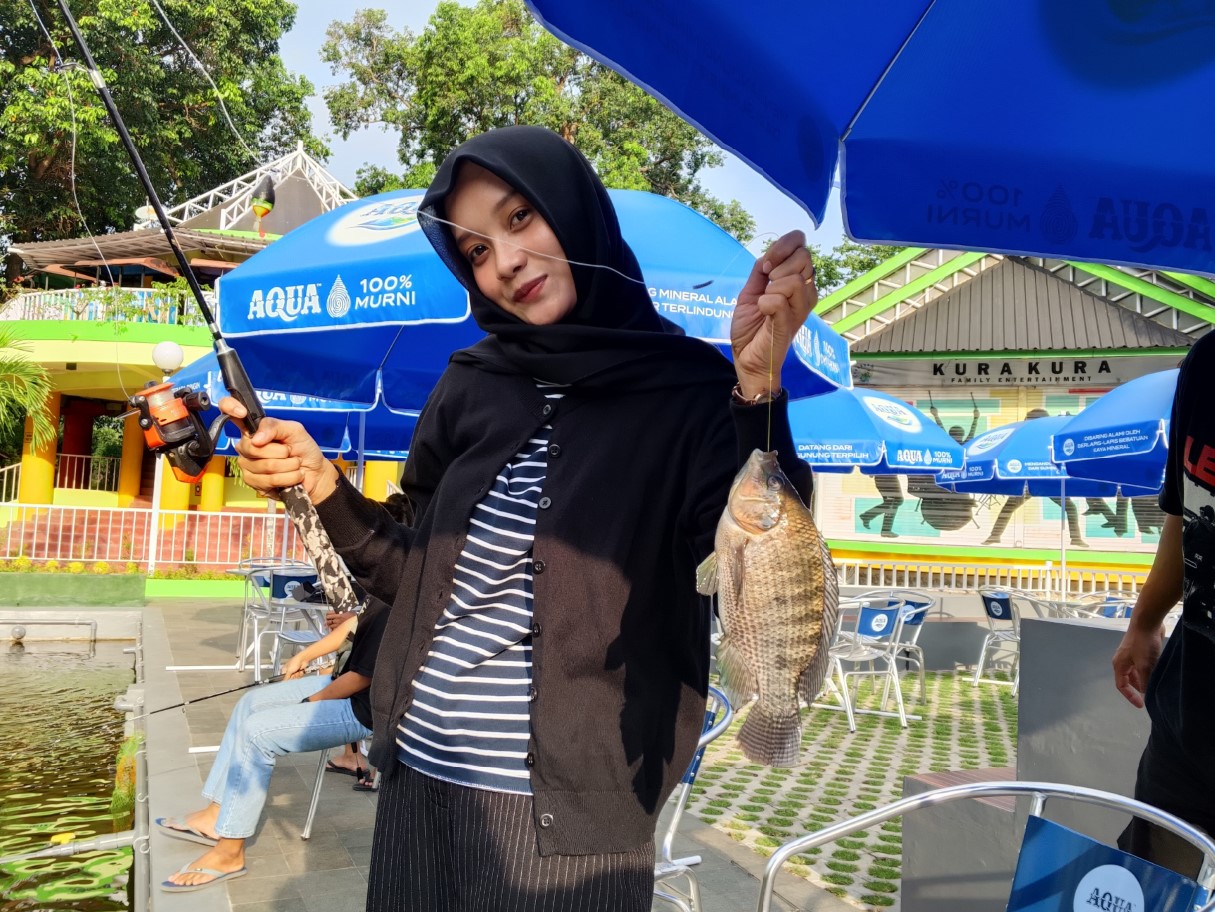 TUNJUKKAN HASIL MEMANCING: Penghobi memancing Isna saat menunjukkan hasil pancingannya di KPK, Mataram, Jumat (11/7).