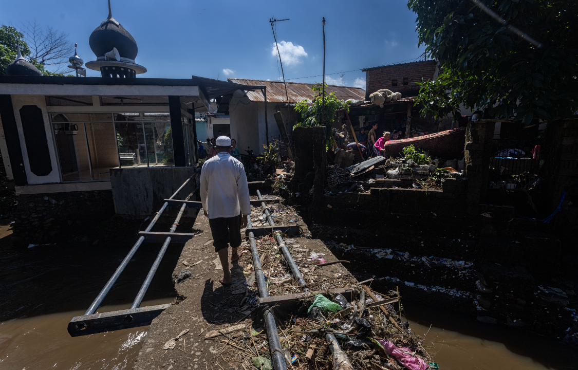 JEMBATAN RUSAK: Seorang warga sedang melintasi jembatan yang rusak akibat banjir beberapa waktu lalu.