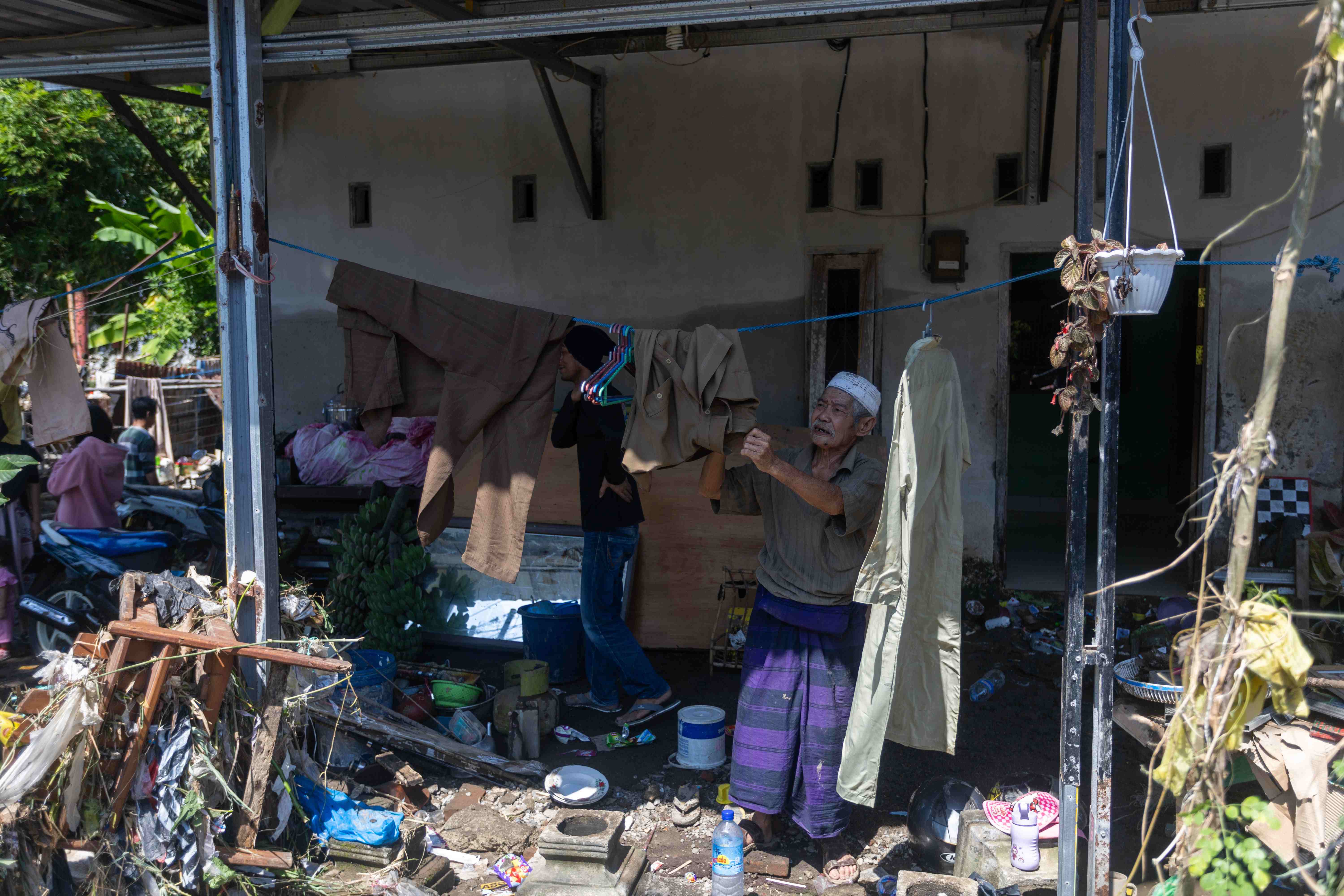 SISAKAN KOTORAN: Seorang warga Kota Mataram membersihkan rumah yang tergenang banjir beberapa waktu lalu.