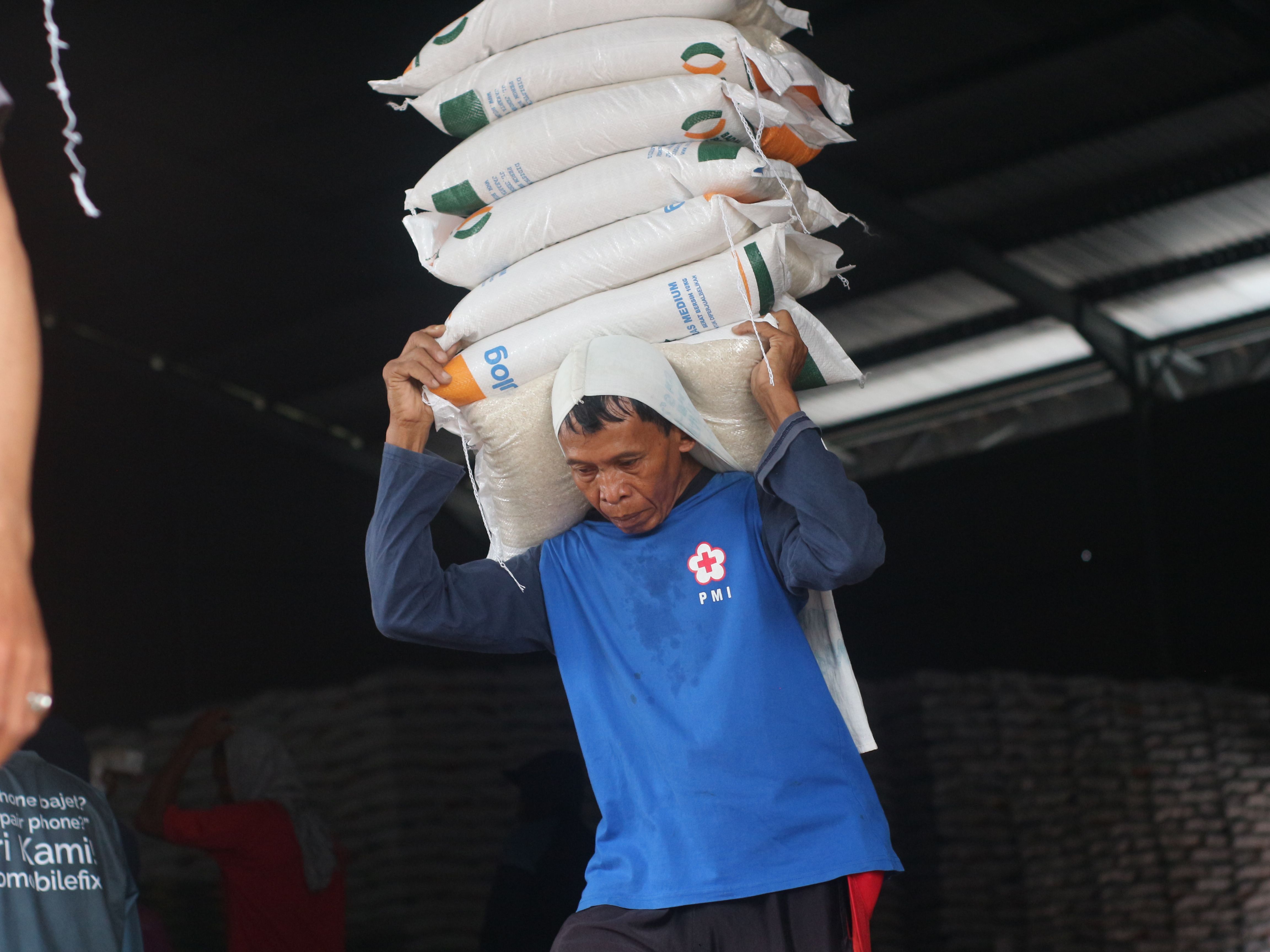 Seorang buruh sedang mengangkut beras di gudang Bulog Lotim.