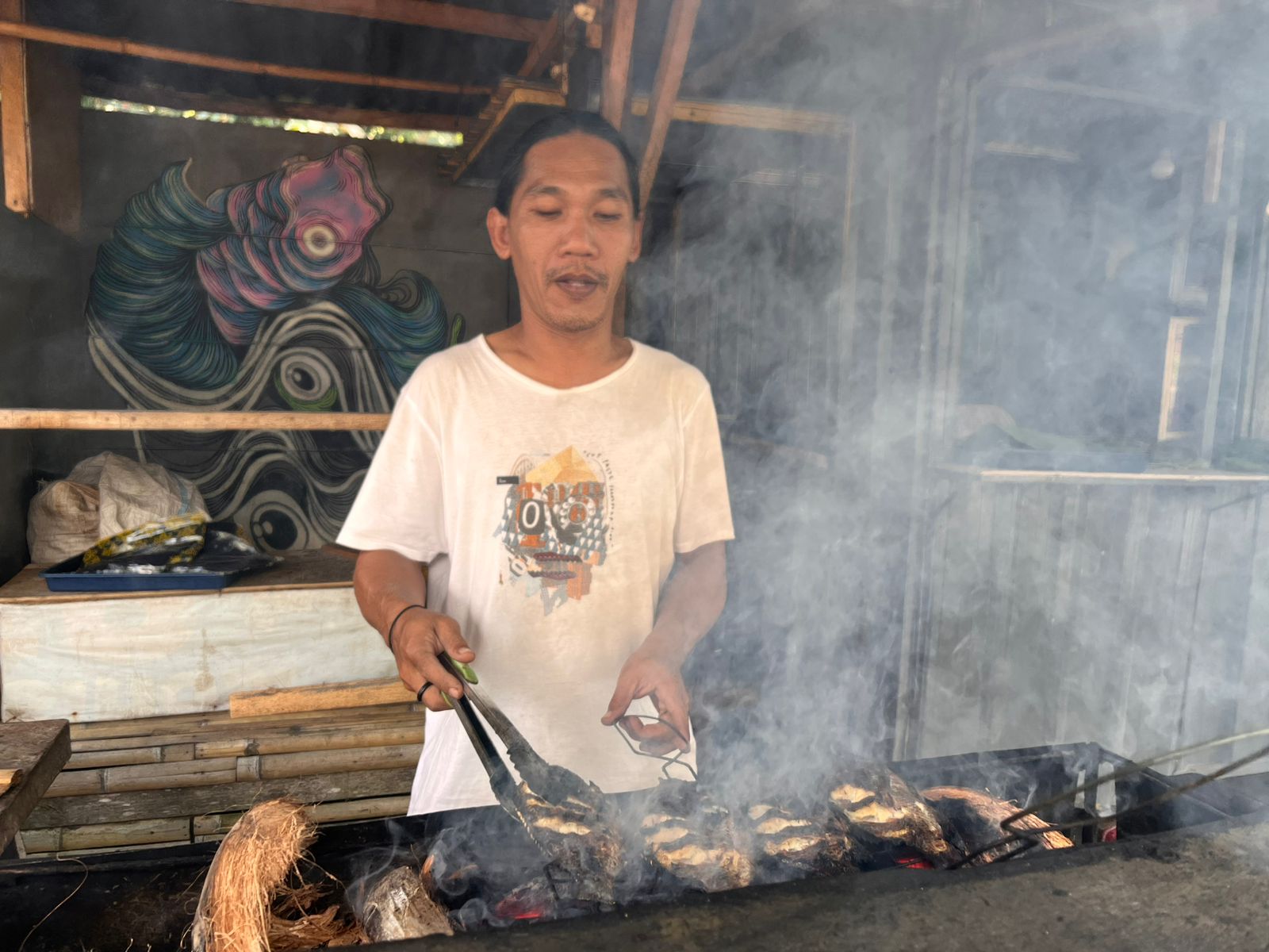 Joko, salah satu pedagang di Lingsar, Lombok Barat membakar pes nila pedas pesanan pembeli, belum lama ini.