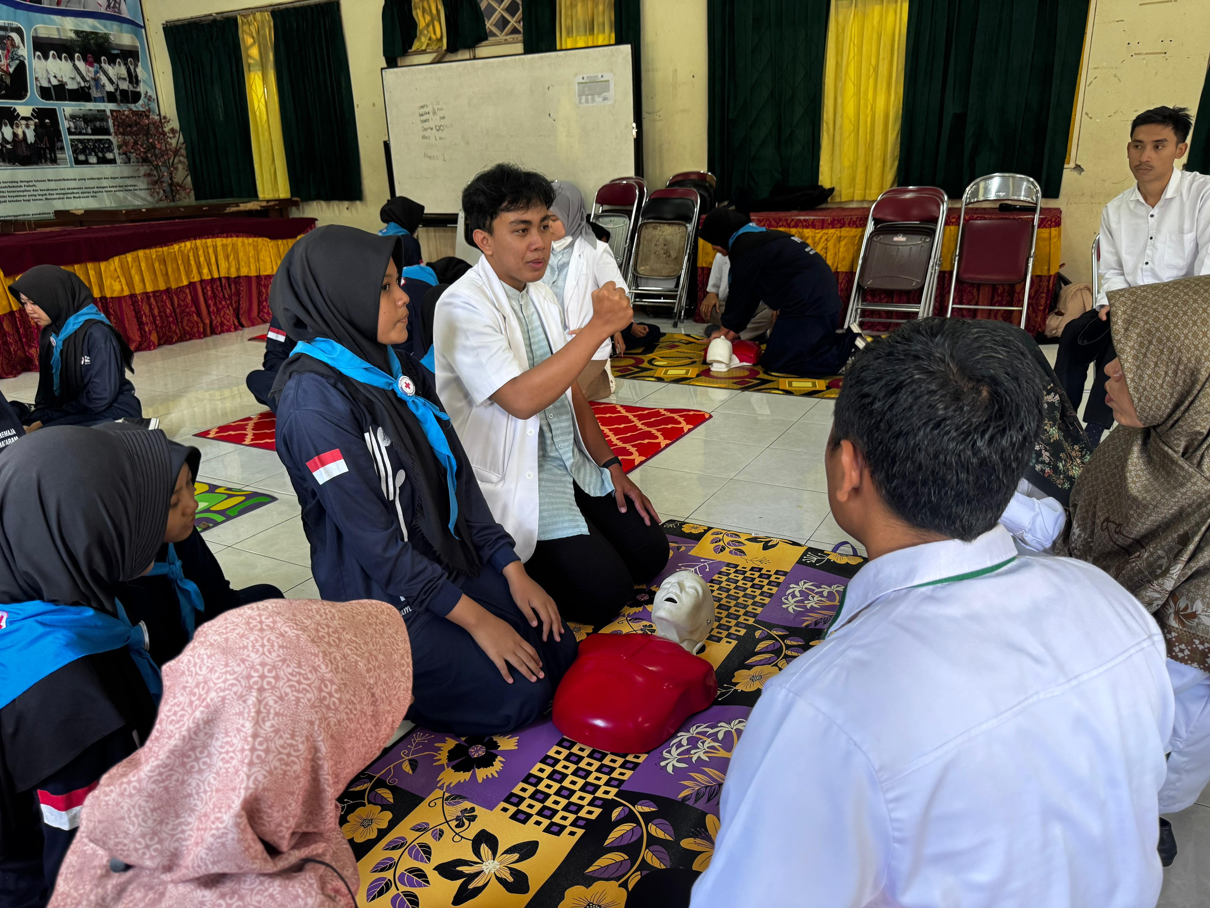Dosen dan dokter muda FKIK Unram melatih siswa MTsN 1 Mataram praktik bantuan hidup dasar menggunakan manekin simulasi henti jantung.
