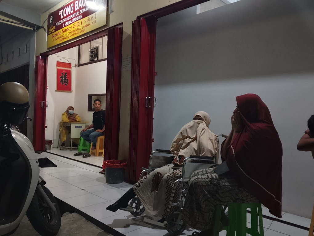 BERHARAP BISA SEMBUH: Seorang pasien duduk di kursi roda antre untuk berobat di Pengobatan Dong Bao, Kota Mataram, Jumat malam (18/7).