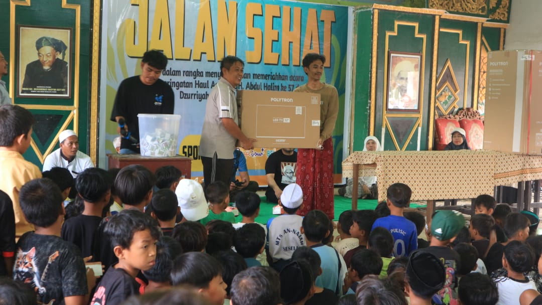 BERIKAN HADIAH: Kepala Desa Sesela Taufik saat menyerahkan hadiah kepada peserta Jalan Sehat Haul TGH Abdul Halim, Sabtu (19/7).