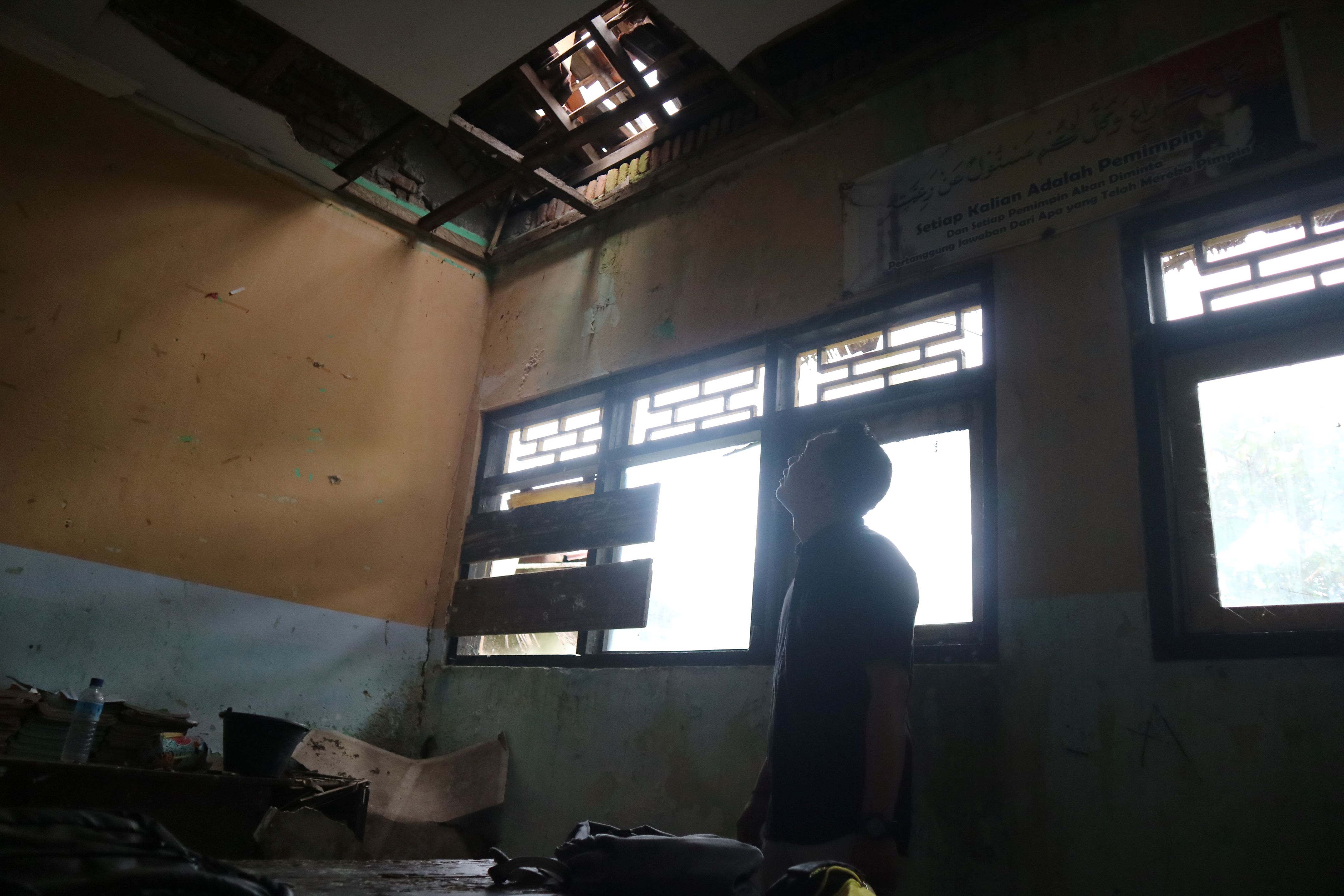 Seorang guru menunjukkan kondisi atap ruang kelas yang rusak parah di SDN 1 Sengkol, Pujut, Lombok Tengah, beberapa waktu lalu.