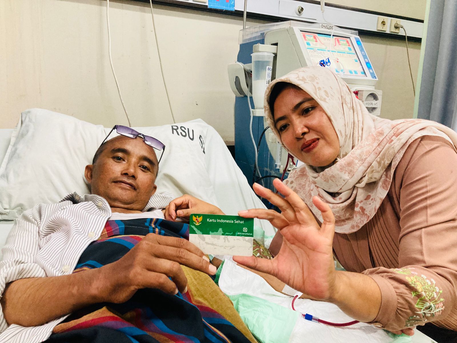 DITANGGUNG BPJS: Lalu Samsu Rizan bersama istrinya Indra Wahyuni memperlihatkan kartu BPJS Kesehatan miliknya saat menjalani perawatan cuci darah di ruang hemodialisa RSUD dr Raden Soedjono Selong.