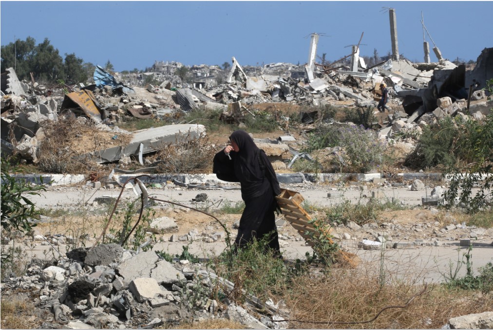 INGIN MERDEKA: Seorang perempuan Palestina minum air sambil mengangkut kayu rakitan di Jalur Gaza, Rabu (30/7).