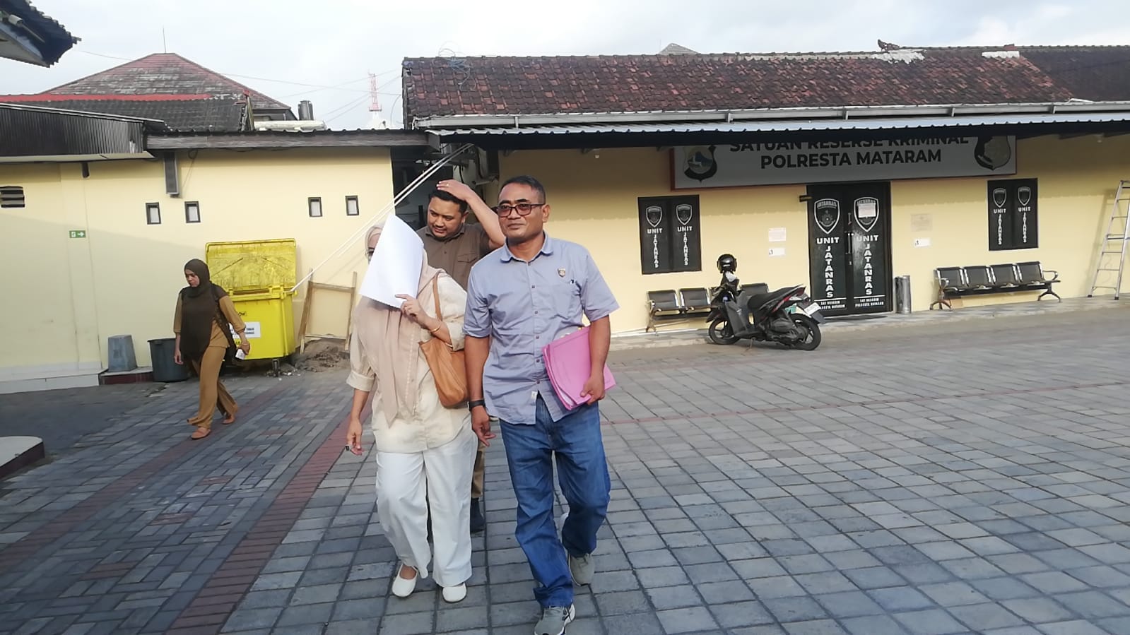 Tersangka korupsi pengadaan masker Rabiatul Adawiyah menutupi dirinya dengan berkas putih saat digiring penyidik ke sel tahanan Mapolresta Mataram, Sabtu (2/8).
