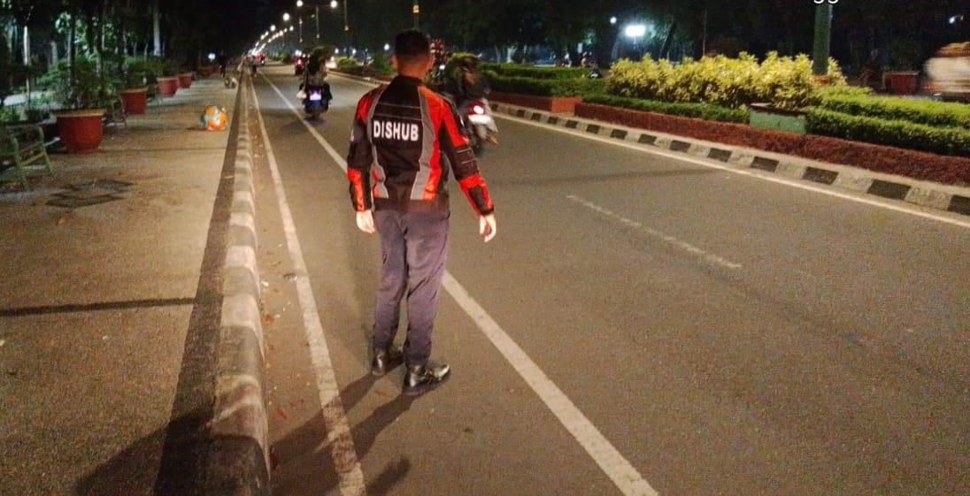 PATROLI: Seorang petugas Dishub tengah mengamankan jalur sepeda di kawasan Udayana, Kota Mataram, Minggu malam (3/8).