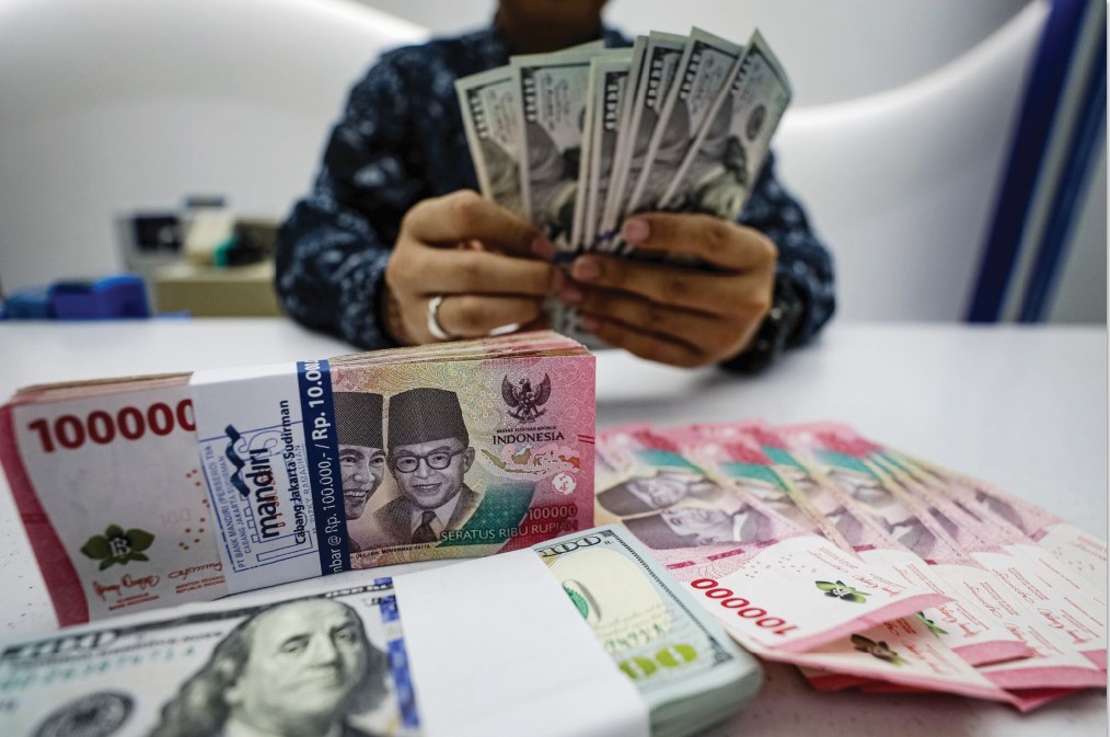 UANG : Pegawai menunjukan mata uang Dolar Amerika dan Rupiah di salah satu kantor cabang bank di Jakarta, Selasa (22/7/2025). (SALMAN TOYIBI/JAWA POS)