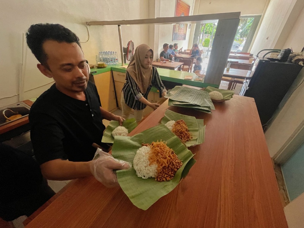 MENU ISTIMEWA: Sigit sedang menyiapkan porsi makanan Nasi Balap Inaq Esun di cabangnya, di jalan Airlangga, Kekalik, Kota Mataram, Kamis (7/8).