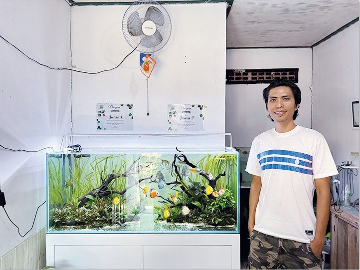 KEBANGGAAN: Pemilik Newnank Aquatiq Lombok Nunang Pradana dengan salah satu karya aquascape buatannya di rumah produksi miliknya. Aquascape ini dirancang dengan detail menyerupai ekosistem air tawar.