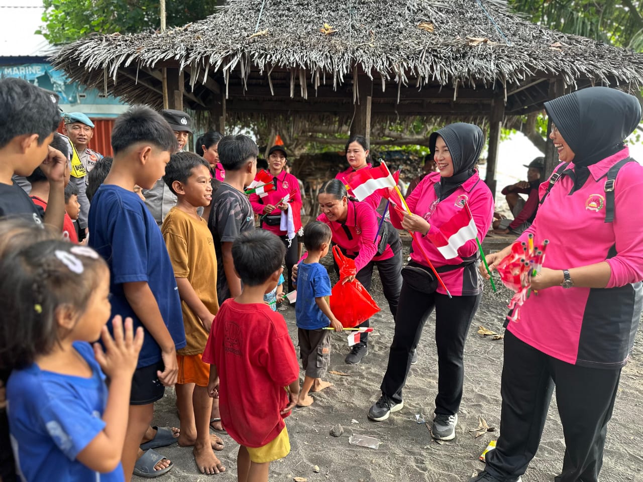 Ketua Bhayangkari Lombok Utara Ny. Heny Agus Purwanta (dua dari kanan) mengajak anak-anak pesisir mengibarkan bendera merah putih.