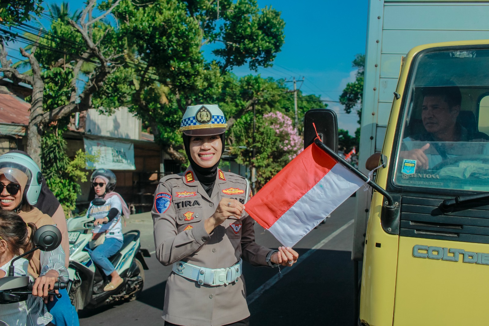 Kasat Lantas Polres Lotim AKP Tira Karista saat membagikan bendera merah putih kepada pengendara roda dua maupun roda empat.