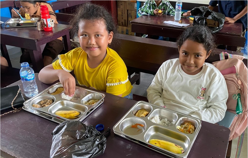 Dua murid di SDN Inpres Kotaraja, Kota Jayapura ketika menikmati MBG pada Selasa (15/4). Untuk menyukseskan MBG, BRIN usulkan pelibatan petani lokal, UMKM, dan BUMDes.