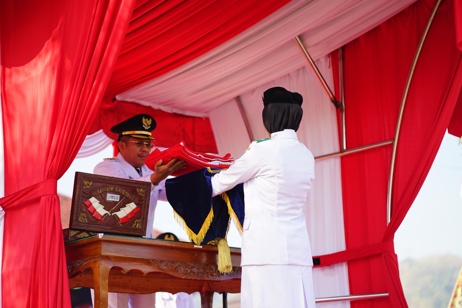 SAKRAL: Bupati Lombok Barat Lalu Ahmad Zaini menyerahkan bendera merah putih kepada pengibar bendera saat perayaan HUT Kemerdekaan RI 17 Agustus.