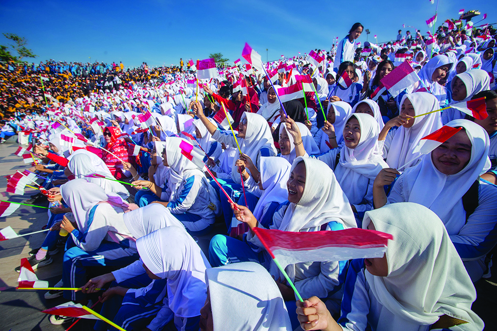 Ribuan siswa berkumpul membawa bendera sambil menyanyikan lagu kebangsaan di Teras Udayana, Kota Mataram.