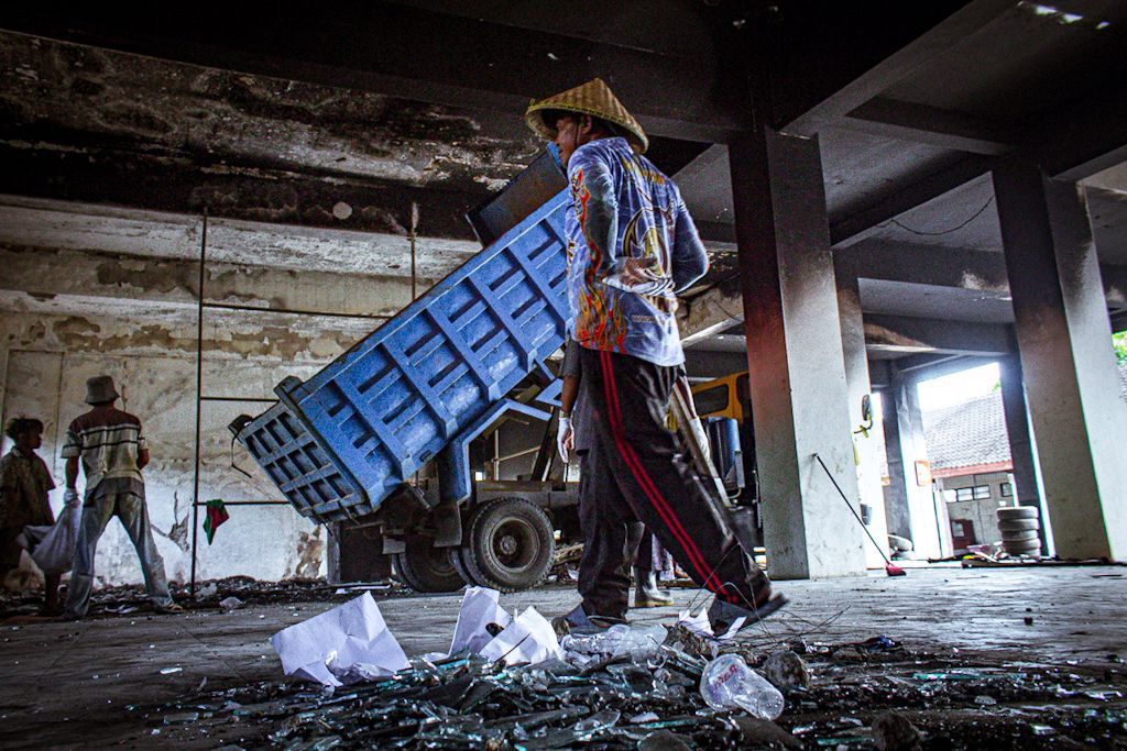 KASUS TETAP BERLANJUT: Sejumlah petugas membersihkan puing-puing di kantor DPRD NTB setelah dibakar.&nbsp;