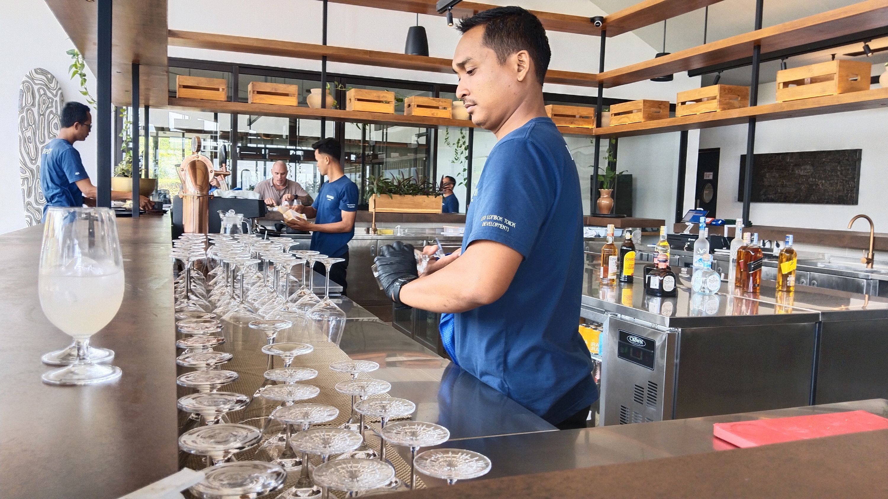 Seorang pramusaji persiapkan deretan gelas di atas meja yang akan disajikan pada pengunjung di Restaurant Kelapa, Samara Lombok, Rabu (9/10).