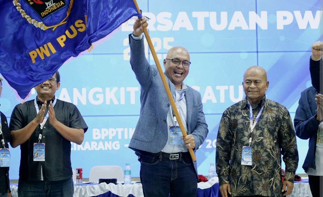 Akhmad Munir mengibarkan pataka PWI usai terpilih sebagai Ketua Umum PWI Pusat dalam Kongres di Cikarang, Bekasi, Sabtu (30/8).