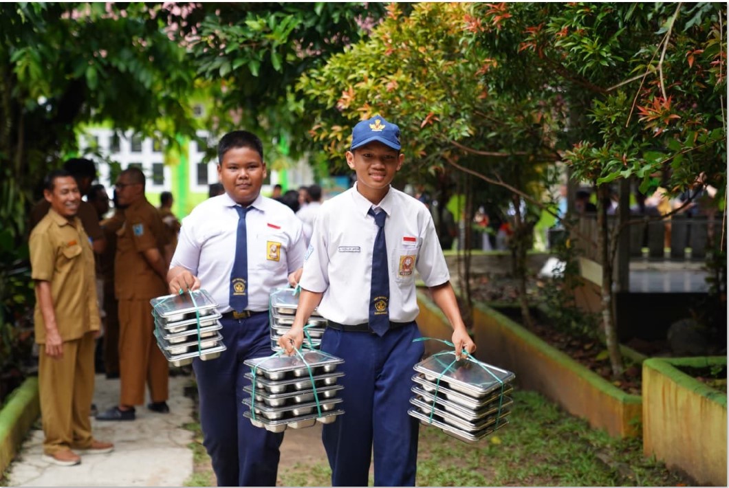 MAKAN GRATIS: Dua siswa SMP 2 Tanah Grogot, Kabupaten Paser, Kaltim membantu mengangkat MBG untuk dibagikan ke rekan-rekannya.
