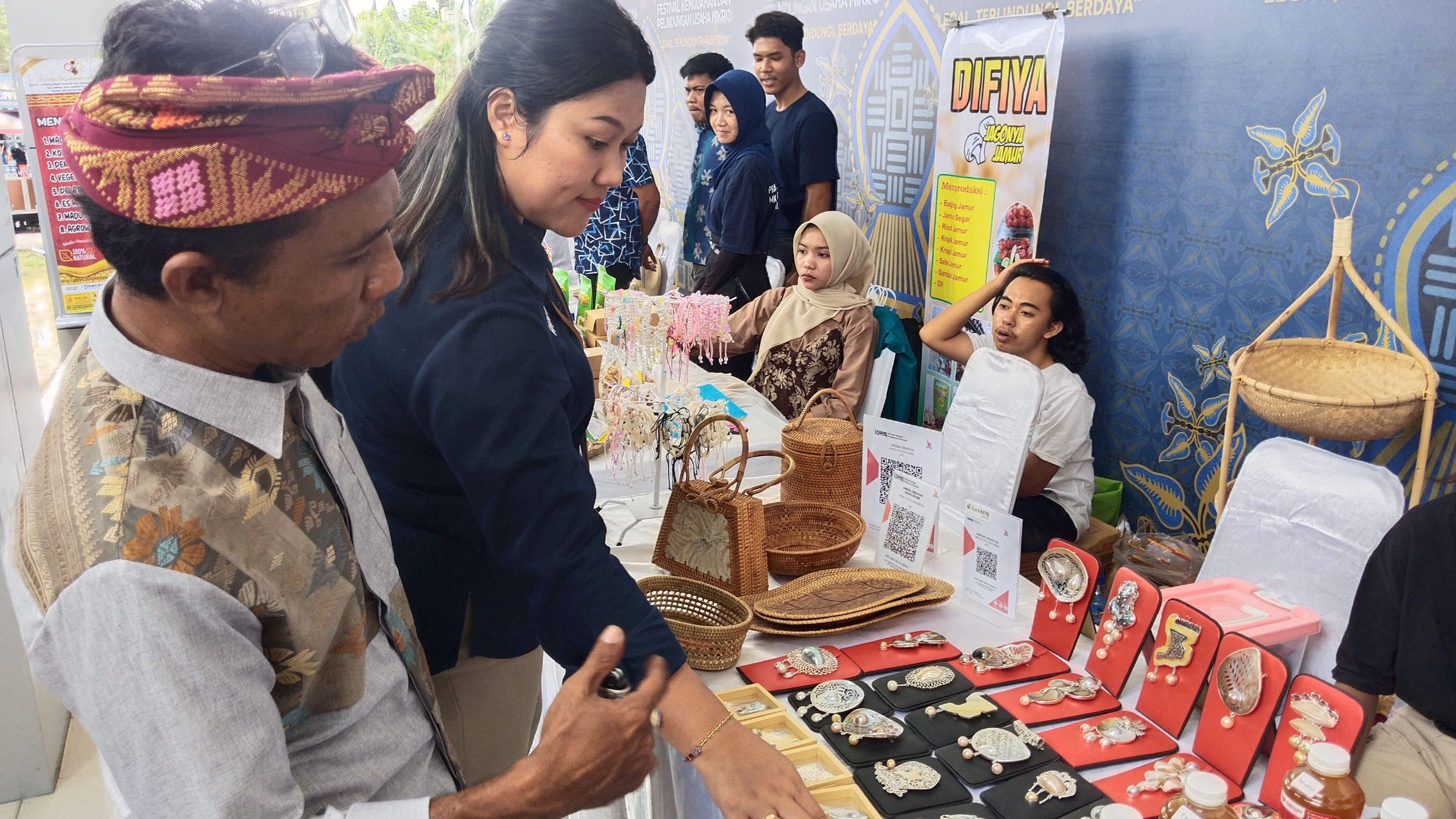 Muhammad Farid Rizki (kiri) menjelaskan keunggulan produk kerajinan perak khas Desa Ungga kepada seorang pengunjung festival.