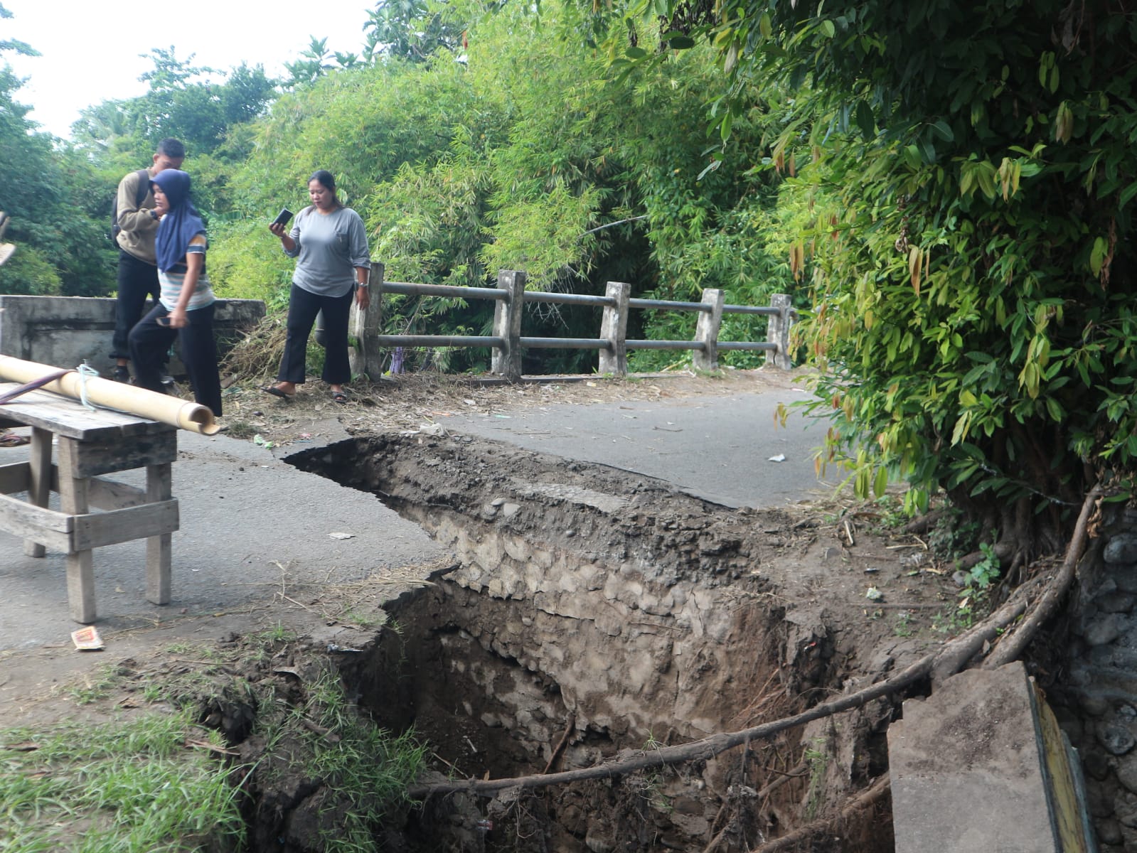 Sejumlah warga sedang melihat jembatan penghubung Desa Teko dan Desa Apit Aik yang nyaris putus akibat di terjang air sungai tanggek
