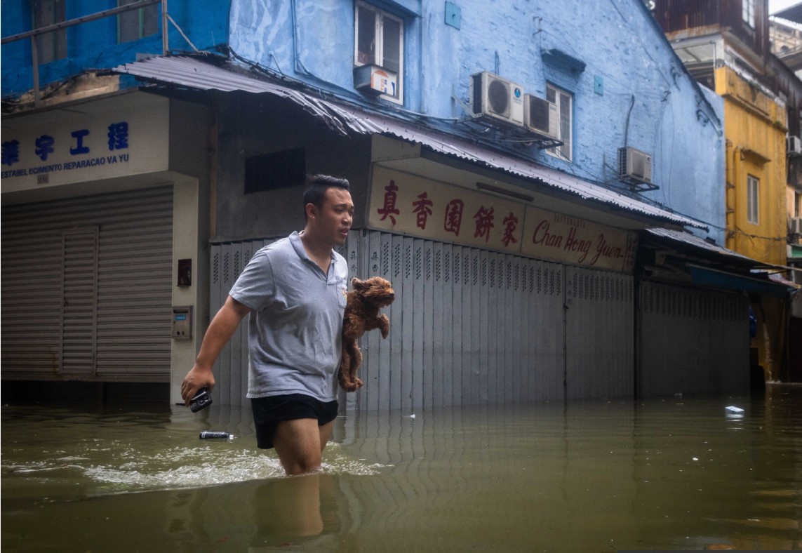 SELAMATKAN DIRI: Seorang pria di Makau mengevakuasi anjing dari banjir akibat Topan Super Ragasa di Makau, Rabu (24/9).