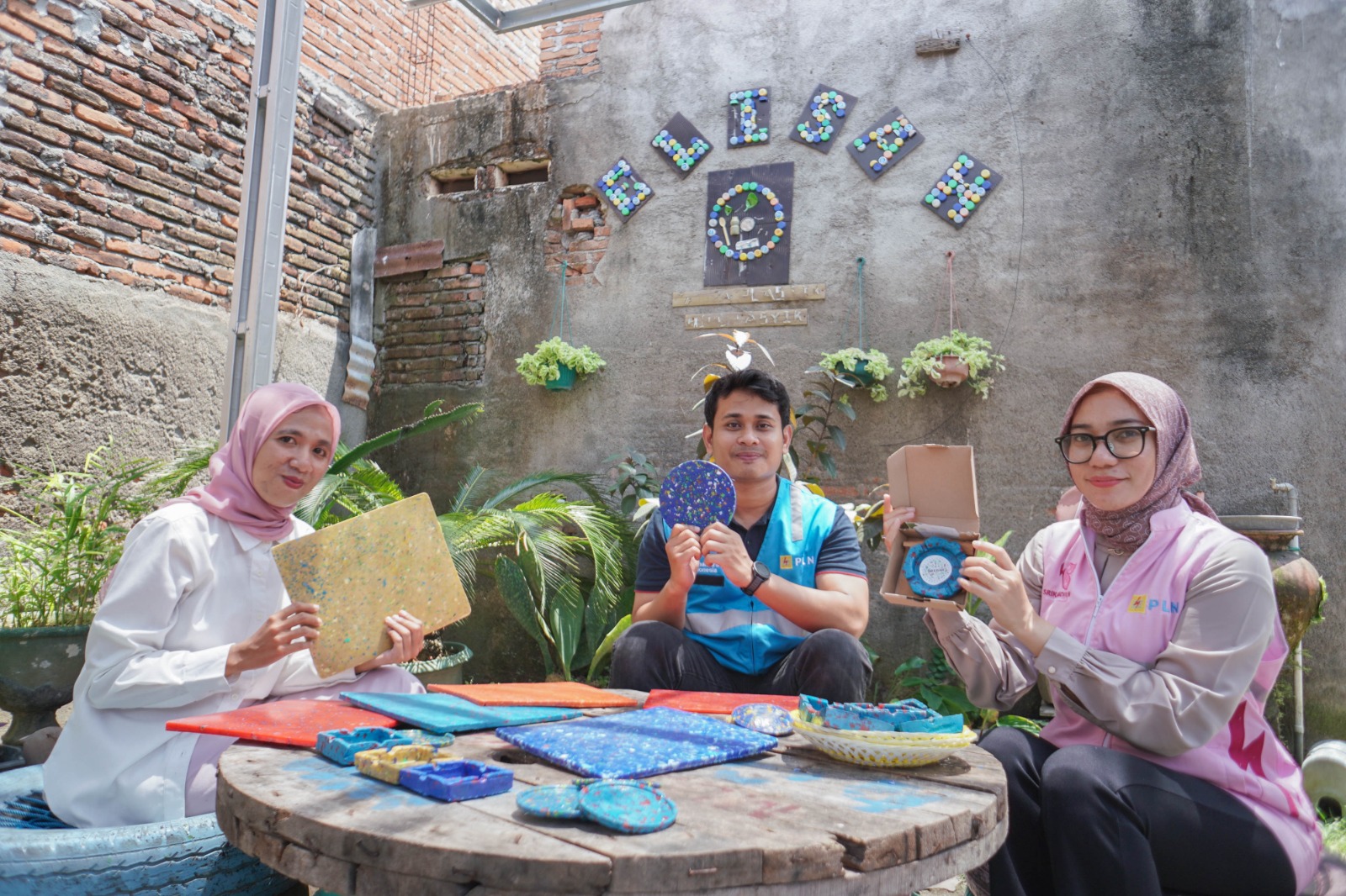 Tim TJSL PLN UIP Nusra bersama pendiri Komunitas GELISAH Lailatul Ulfah (kiri) memamerkan berbagai produk dari sampah botol plastik program bottle up.