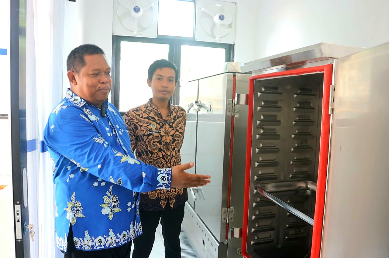 SESUAI STANDAR: Ketua Yayasan Agniya I Hariyanto (depan) bersama Kepala SPPG Montong Are 2 Lalu Den Nune Ali menunjukkan rice timer untuk memasak nasi.