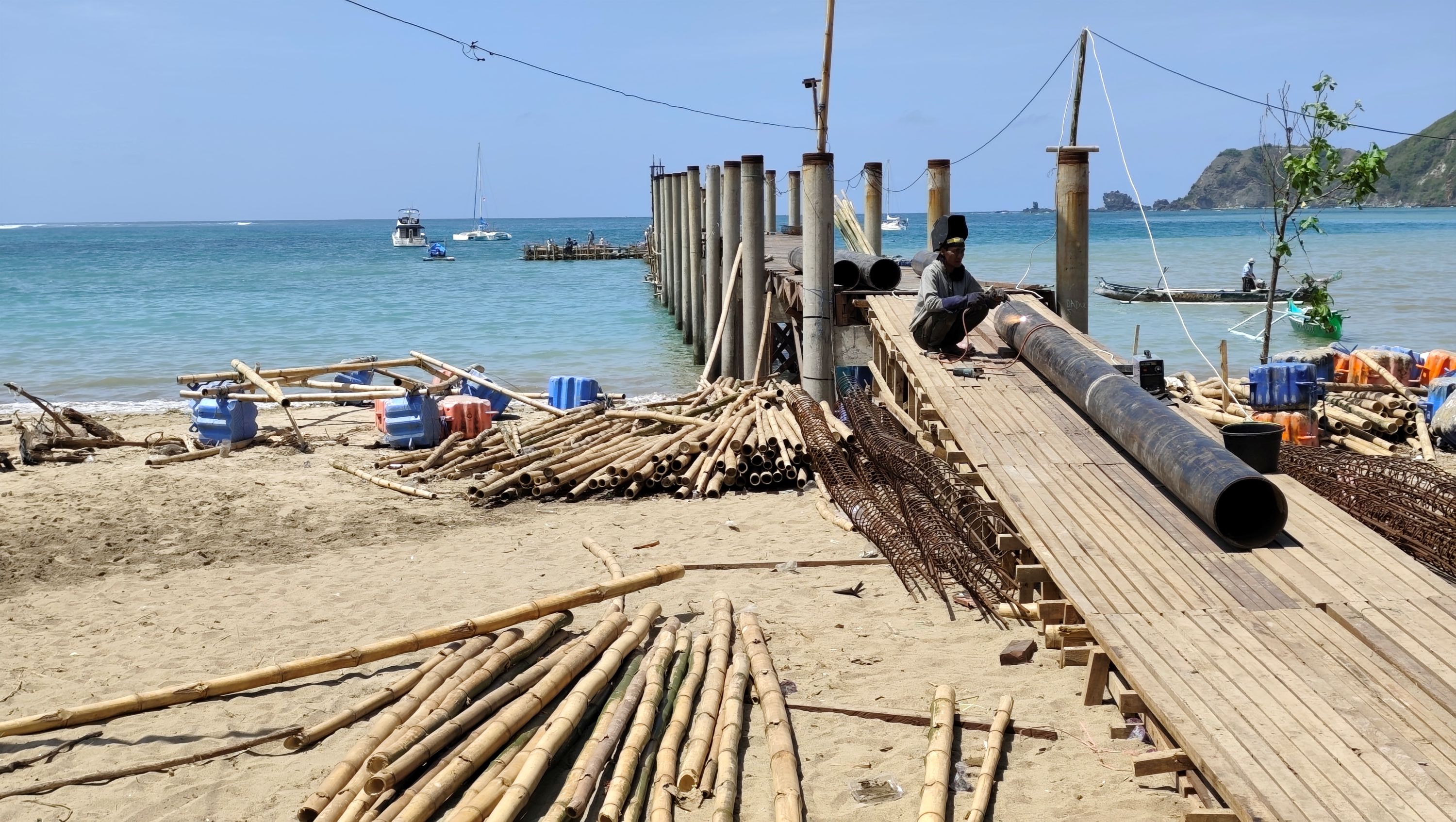 DIKEBUT: Seorang pekerja sedang memperbaiki dermaga apung di pesisir Pantai Kuta, Desa Kuta, Pujut, Loteng, Jumat (26/9) lalu.