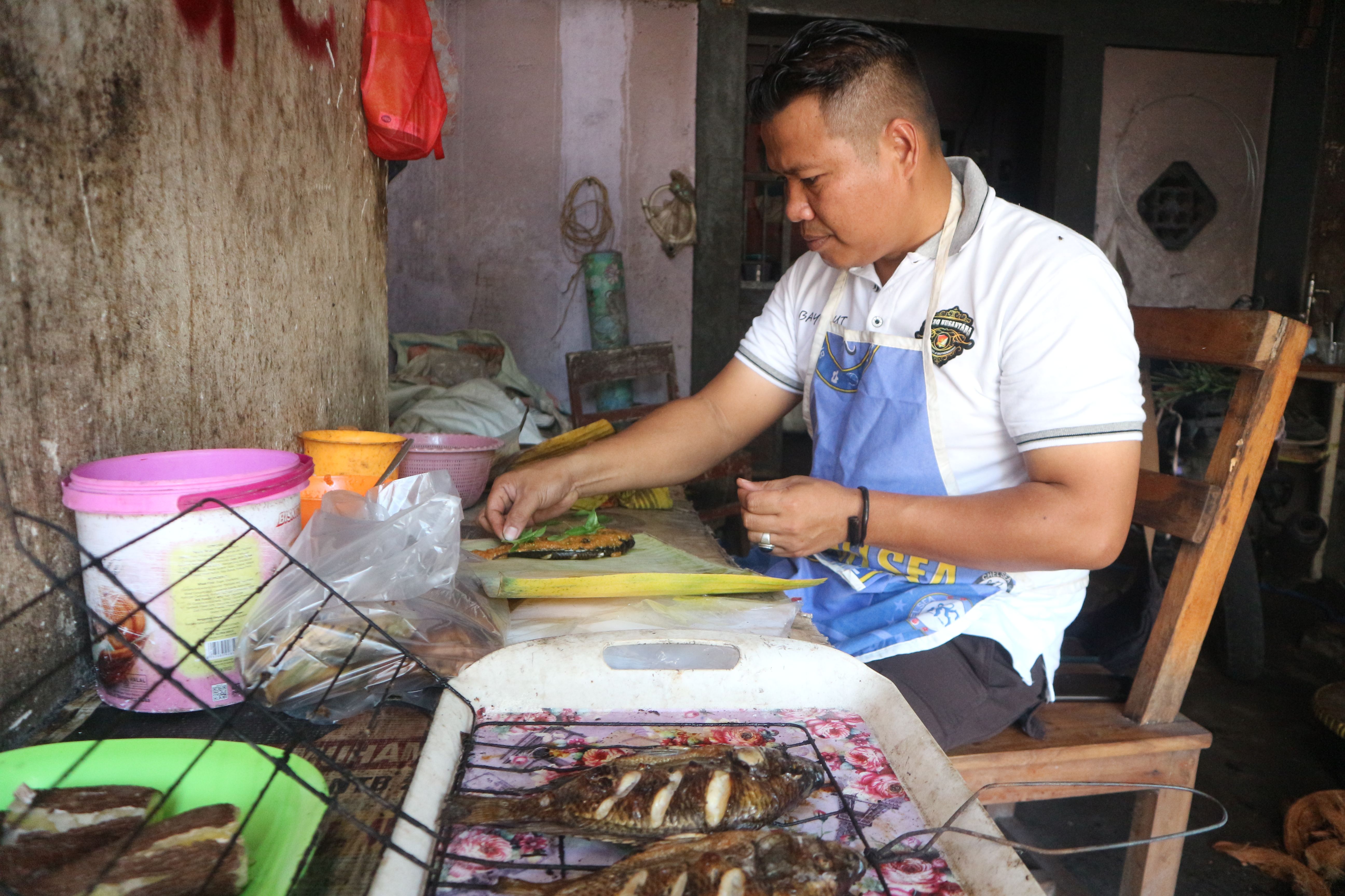 Aipda Abdul Gani menaruh bumbu pada ikan yang nantinya dibungkus dengan daun pisang kemudian dibakar, sehingga menjadi hidangan menggugah selera.