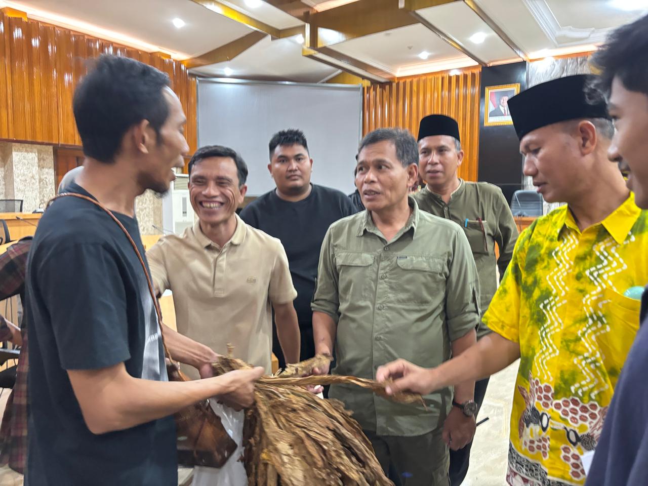 BUTUH SOLUSI: Plt Kepala Distanbun NTB Muhammad Riadi (baju kuning) memeriksa tembakau yang dibawa petani, pada pertemuan yang digelar di Kantor Gubernur NTB, beberapa waktu lalu.