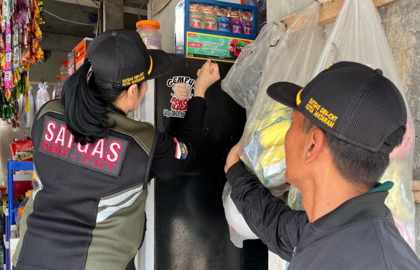 Anggota Satgas memasang stiker Gempur Rokok Ilegal di salah satu toko kelontong.