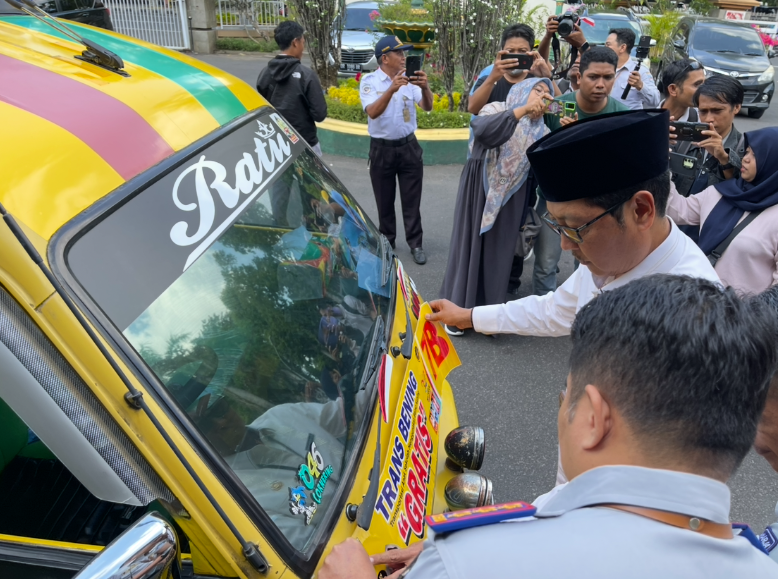 Sekda Kota Mataram Lalu Alwan Basri memasang stiker transportasi gratis pelajar di bemo kuning.