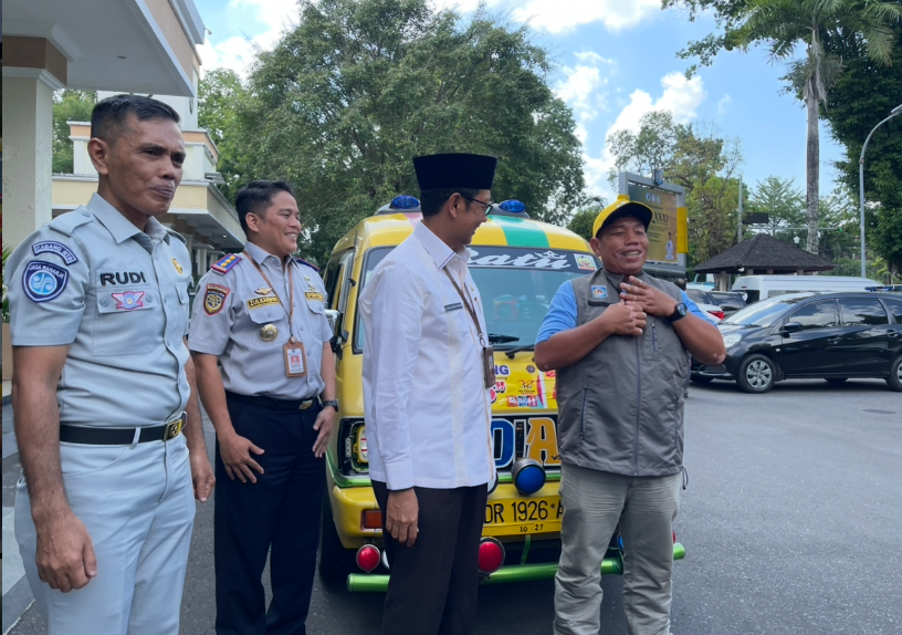 Driver Trans Bening memasang jaket sebagai atribut khusus disaksikan Sekda Lalu Alwan Basri dan Kadishub Zulkarwin.