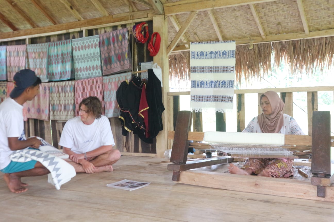 Naim, saat menjelaskan proses pembuatan kain songket kepada slah seorang tamu asing di Hand Weaving miliknya di Desa Tetebatu, Minggu (5/10)