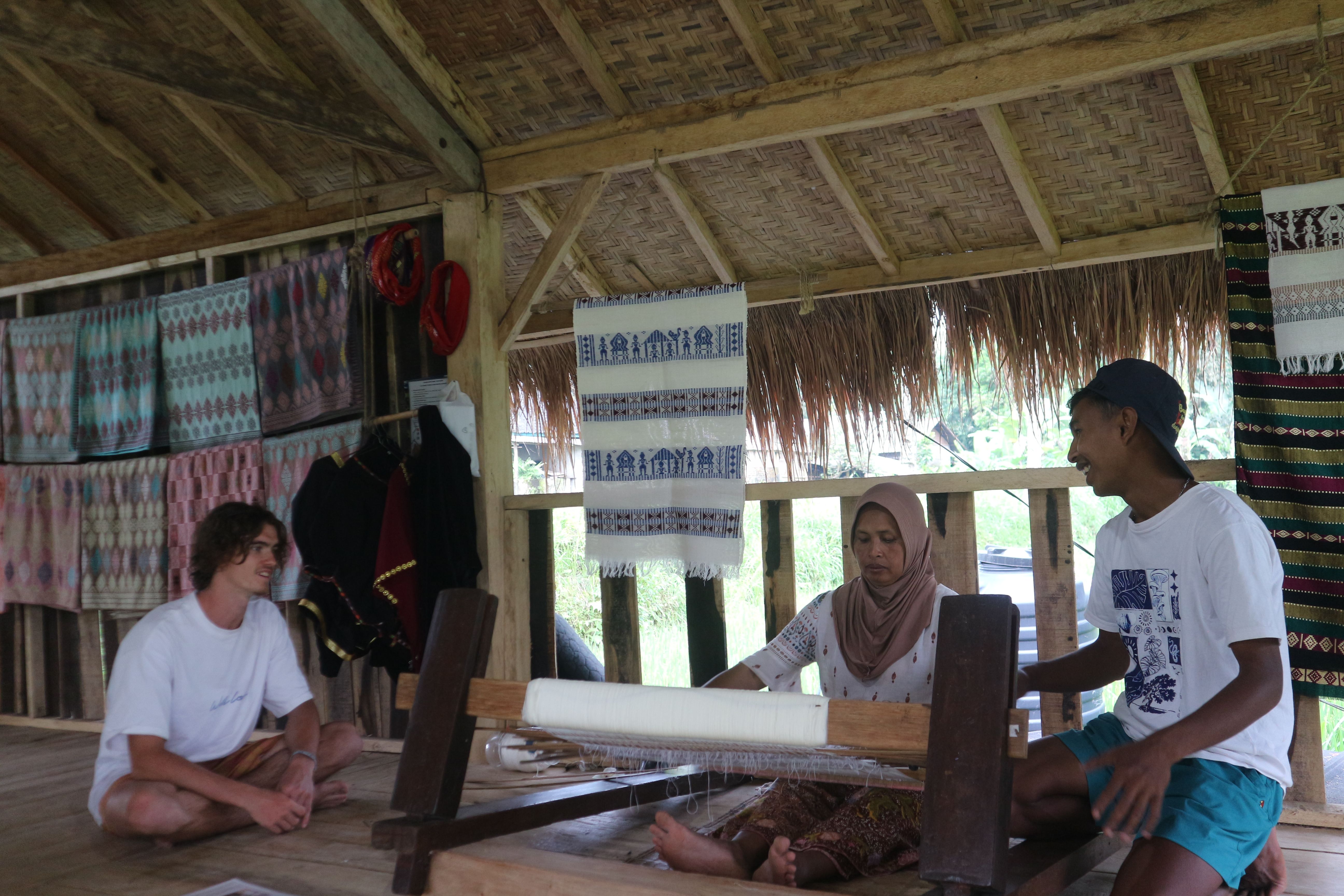Naim sedang menjelaskan cara kerja alat tenun tradisional kepada wisatawan asing