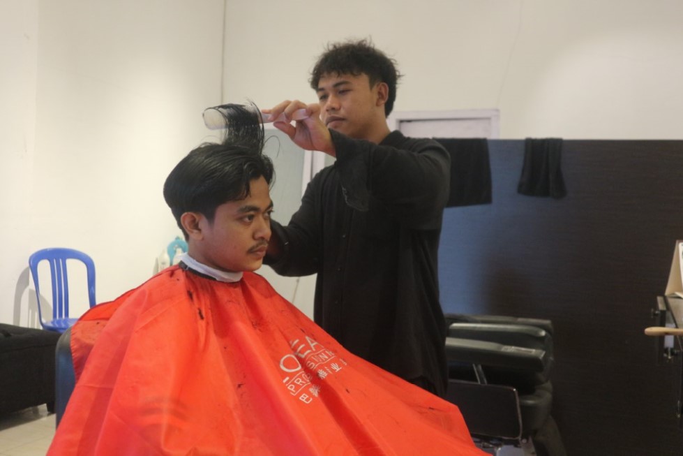 KONSENTRASI: Alik, 22 tahun seorang capster di salah satu barbershop di Pancor sedang mencukur pelanggannya, Jumat (3/10).