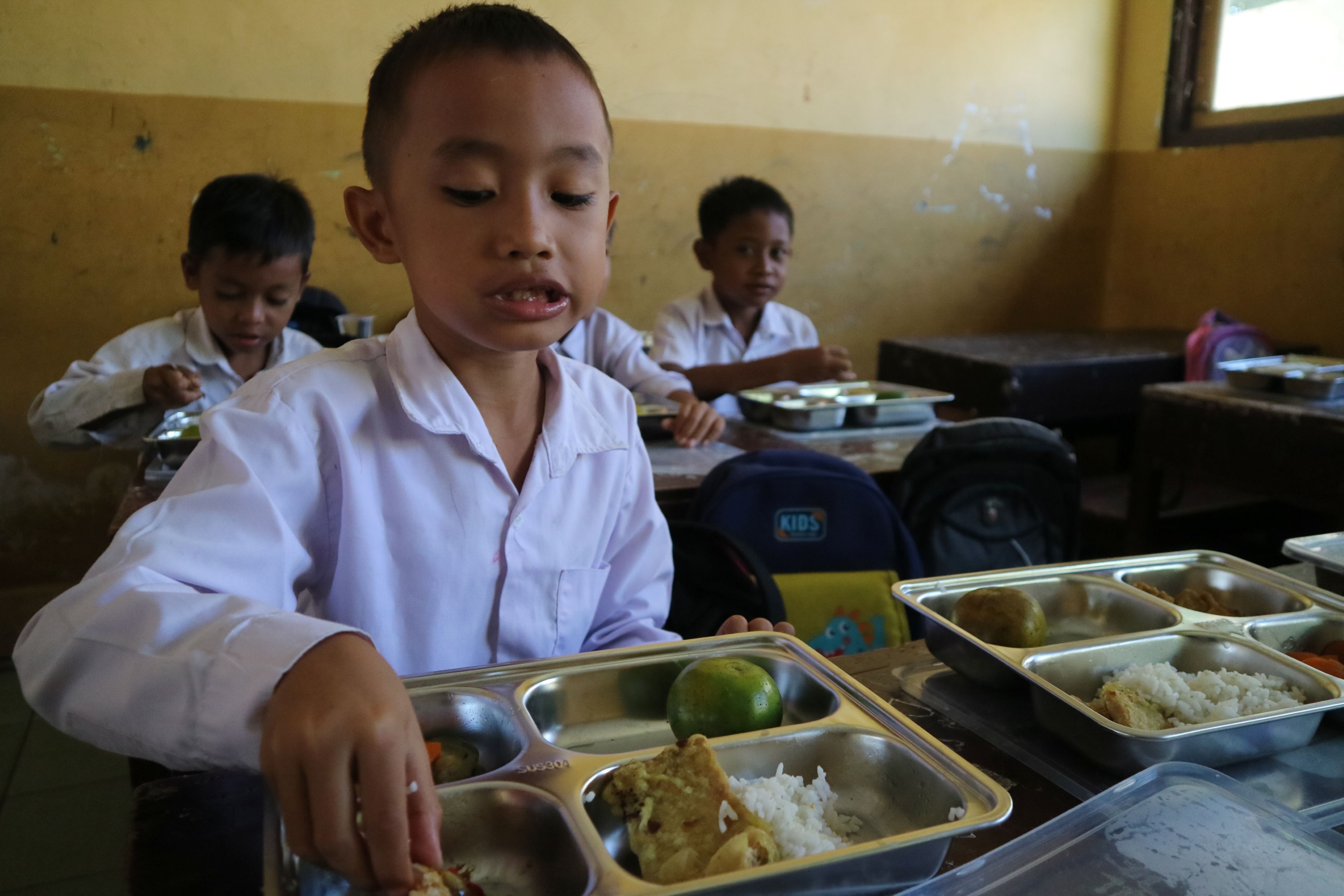 EVALUASI MBG: Seorang anak sekolah dasar menikmati dengan lahap paket makanan bergizi gratis di sekolah, Lombok Tengah, beberapa waktu lalu.