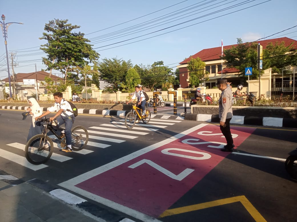 SETIAP PAGI: Anggota Polsek Tanjung membantu siswa SMPN 1 Tanjung menyeberangi jalan