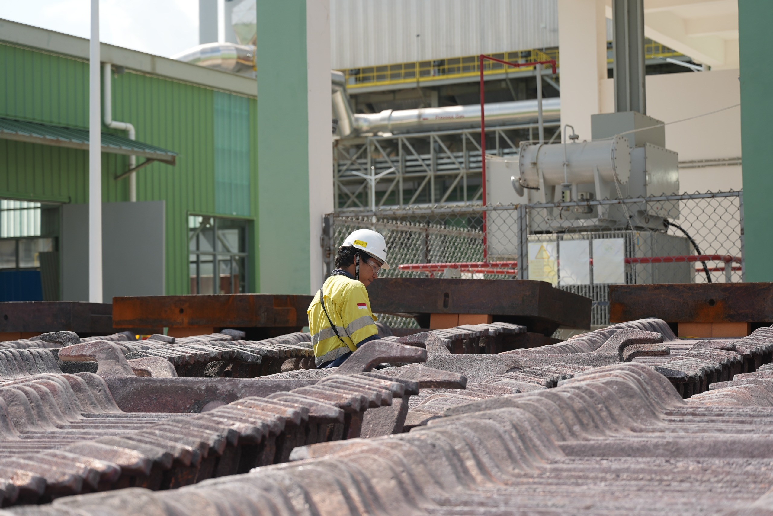Pekerja smelter AMMAN saat berada di tengah tumpukan katoda tembaga yang berhasil dicetak dari tungku smelter.