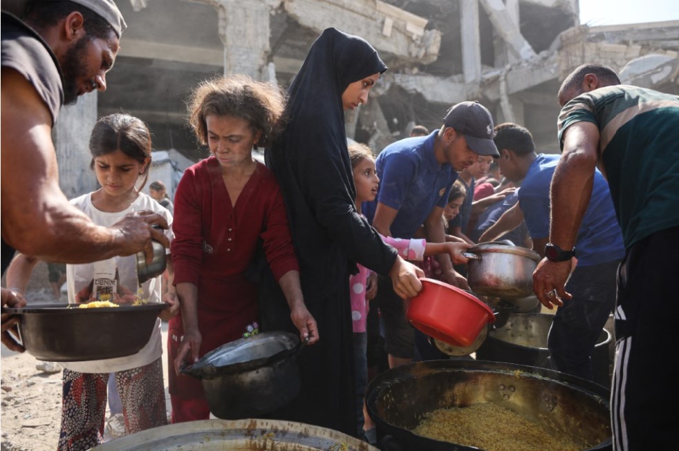 Warga Palestina mengantre bantuan makanan di luar Masjid Imam al-Shafi&rsquo;i yang rusak di Zeitoun, Kota Gaza, Kamis (23/10).