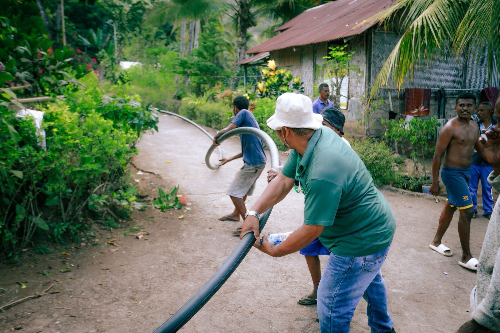 Petugas PLN bersama perwakilan Yayasan PAPHA dan masyarakat menarik pipa untuk mengalirkan air bersih.