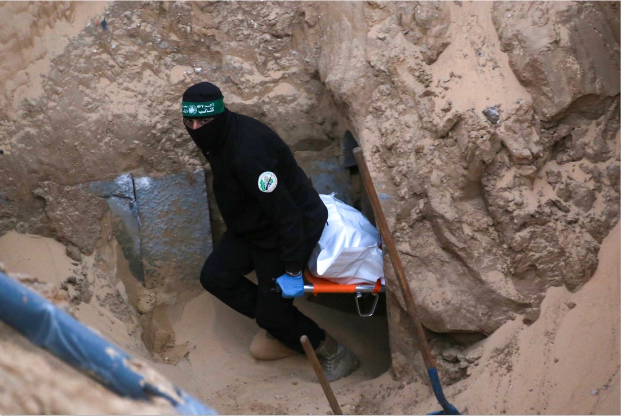KOMITMEN TERUSIK: Seorang militan Hamas mengambil jenazah sebagai bagian dari penyerahan sandera oleh Israel dari sebuah terowongan di wilayah utara Khan Yunis, Jalur Gaza, Jumat (29/10).