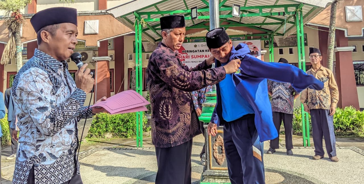 Kepala MAN Lobar H Abdul Azis Faradi memasangkan jaket kepada siswanya Imam Pasha yang akan berlaga pada ajang POPNAS 2025 di halaman madrasah setempat, Rabu (29/10).