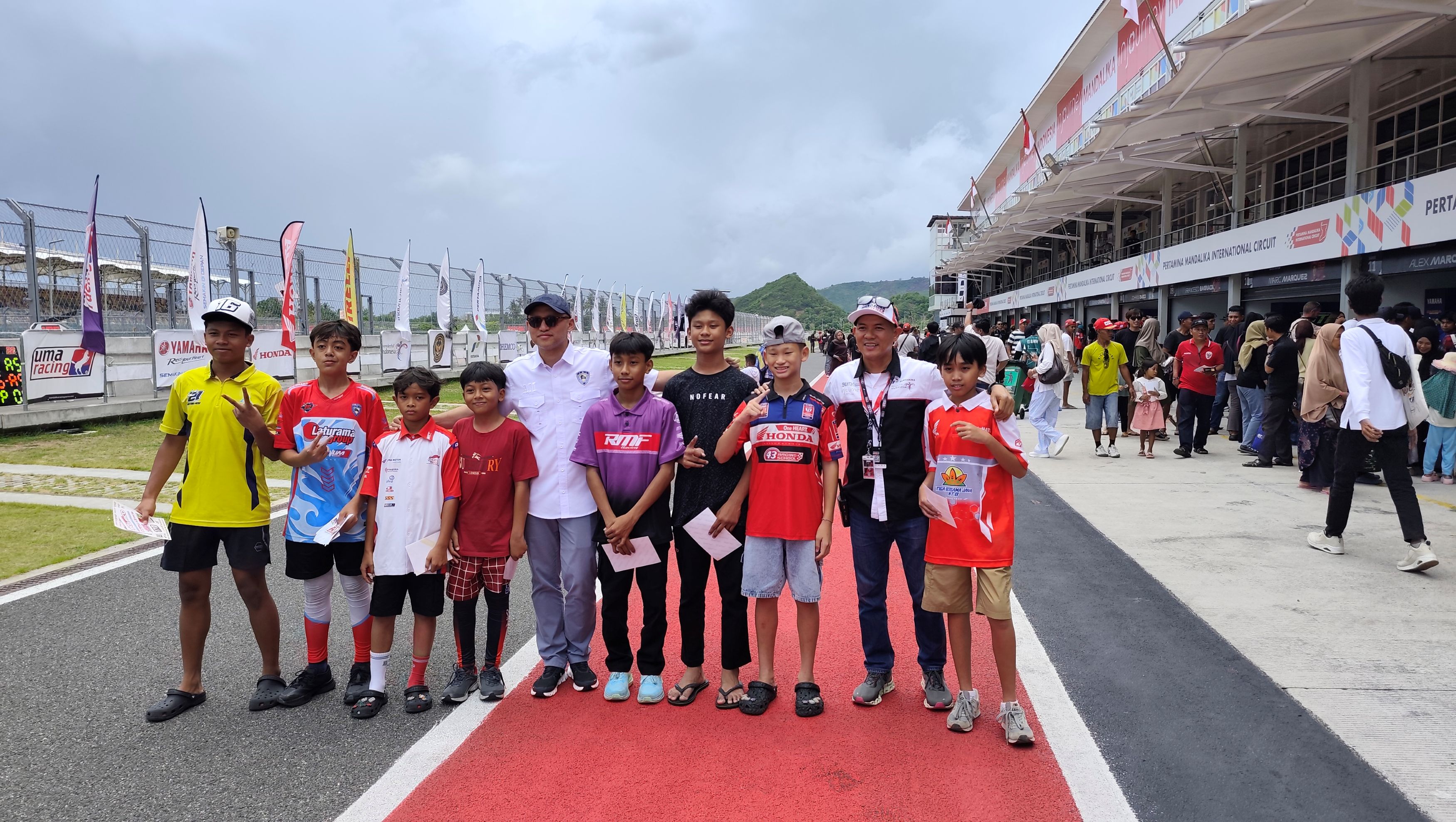 Wakil Ketua Umum Olahraga Prestasi PP Ikatan Motor Indonesia (IMI) Ananda Mikola (lima kiri) berfoto bersama anak-anak yang mengikuti sesi Pit Walk di ajang Mandalika Racing Series 2025 putaran final